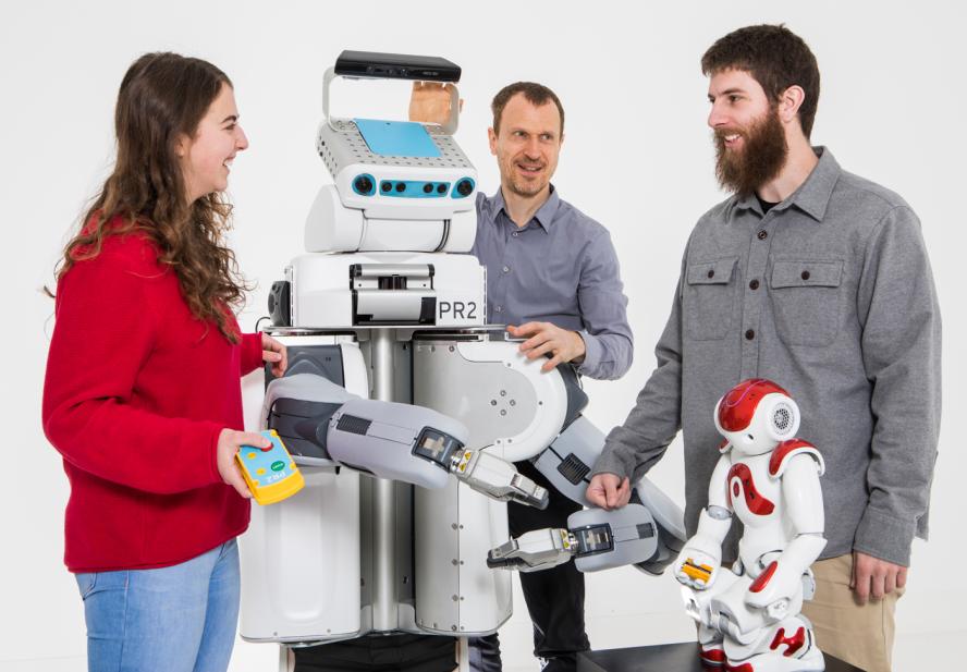 Theresa Law (left), 1G and PhD candidate, Matthias Scheutz,Professor of Computer Science, and Tyler Frasca, 3G and PhD candidate, pose for a photo in the human robot interaction laboratory