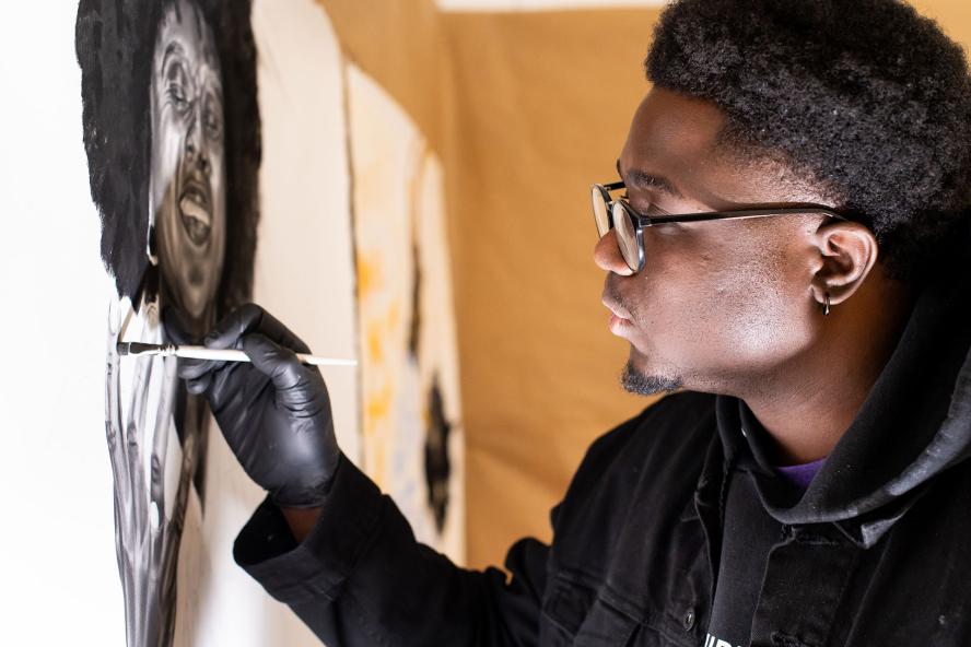 Male graduate student painting, in studio
