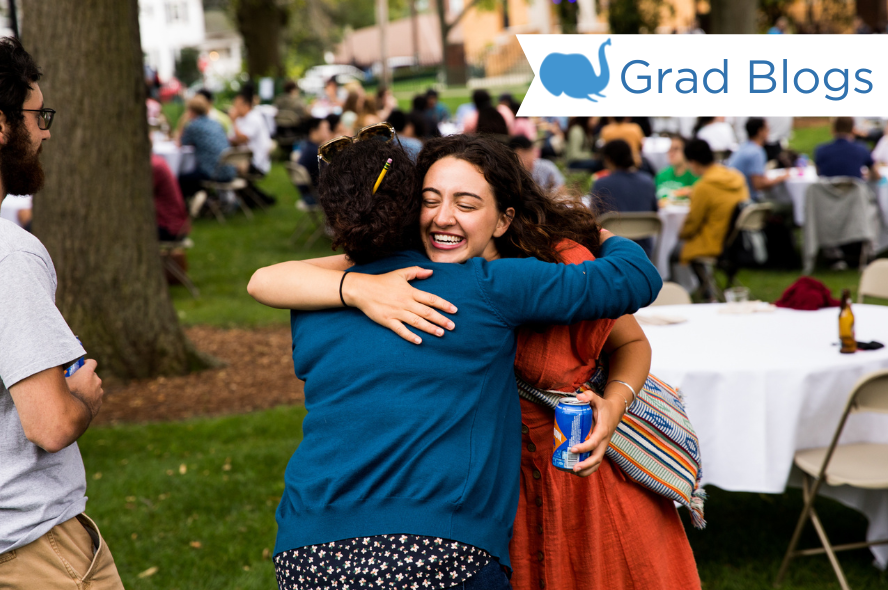 Two students hug in greeting at a community picnic