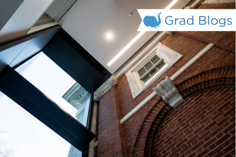 An upward photo shot of a brick wall with tall windows, the inside of a Tufts building