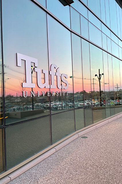 Tufts University logo on the Joyce Cummings Center, reflecting the sunset